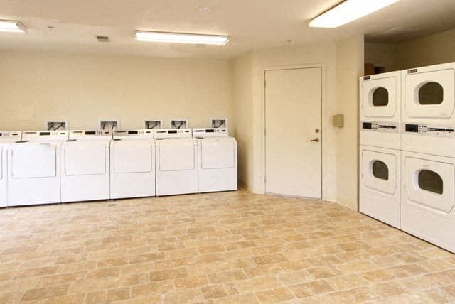 an empty laundry room with white washers and dryers